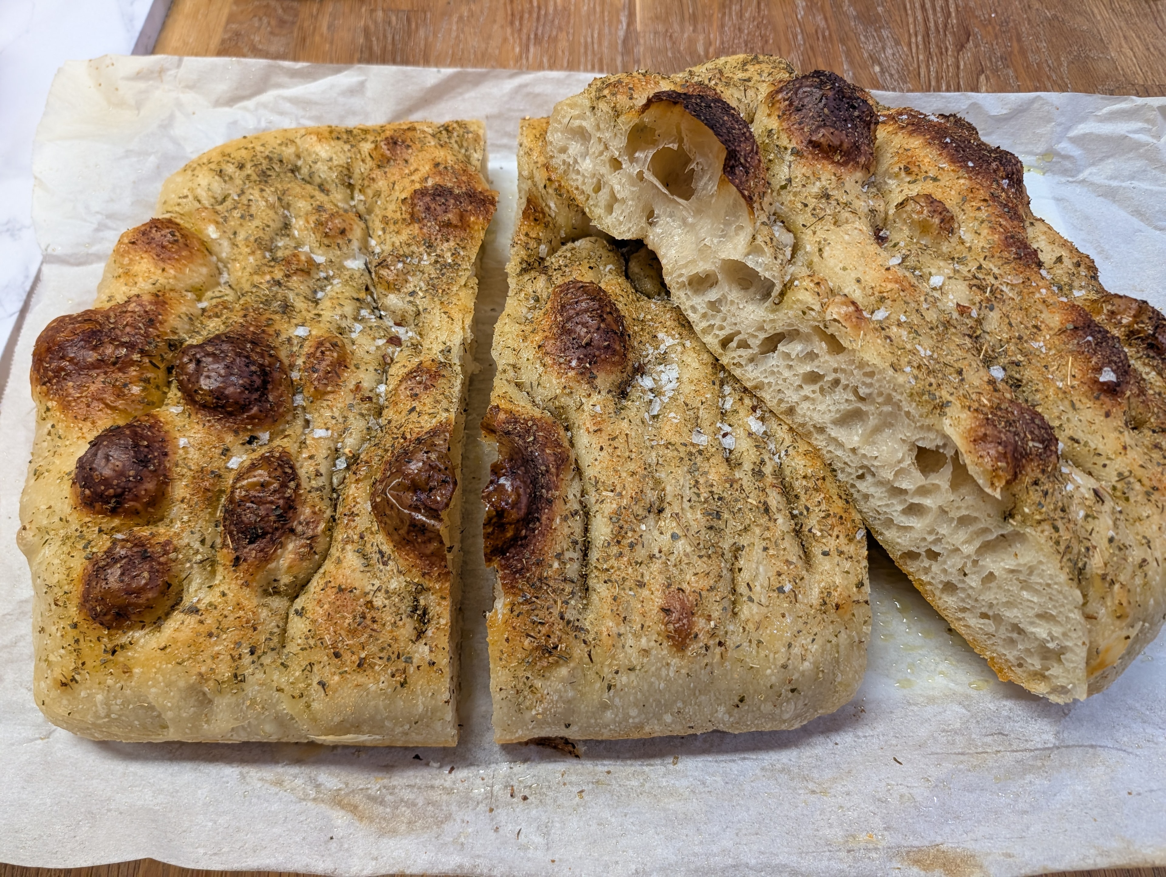 Herb focaccia with caramelized olives torn open to show airy crumb