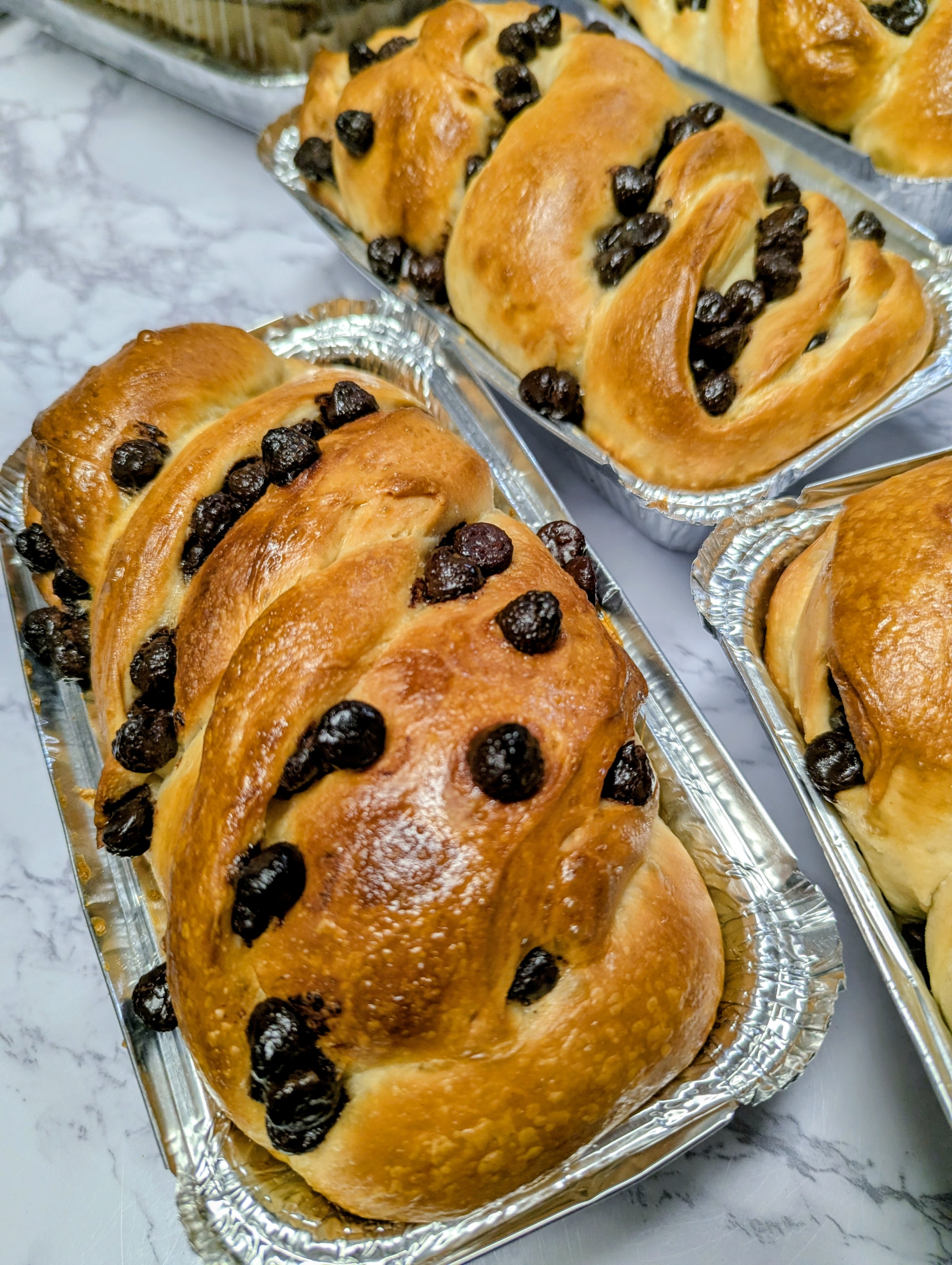 Braided chocolate chip brioche loaves in foil pans