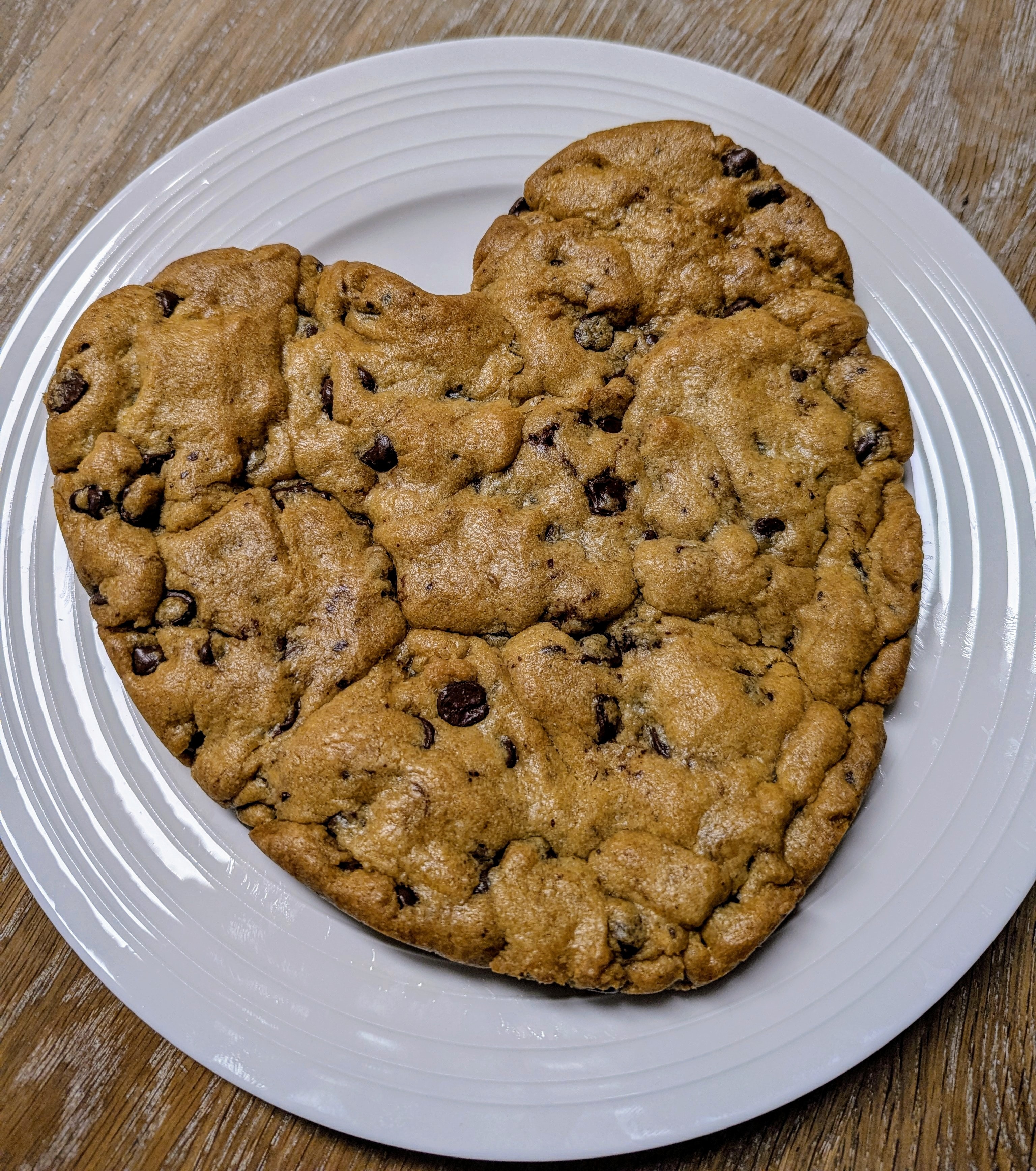 Heart-shaped giant chocolate chip cookie on a white plate