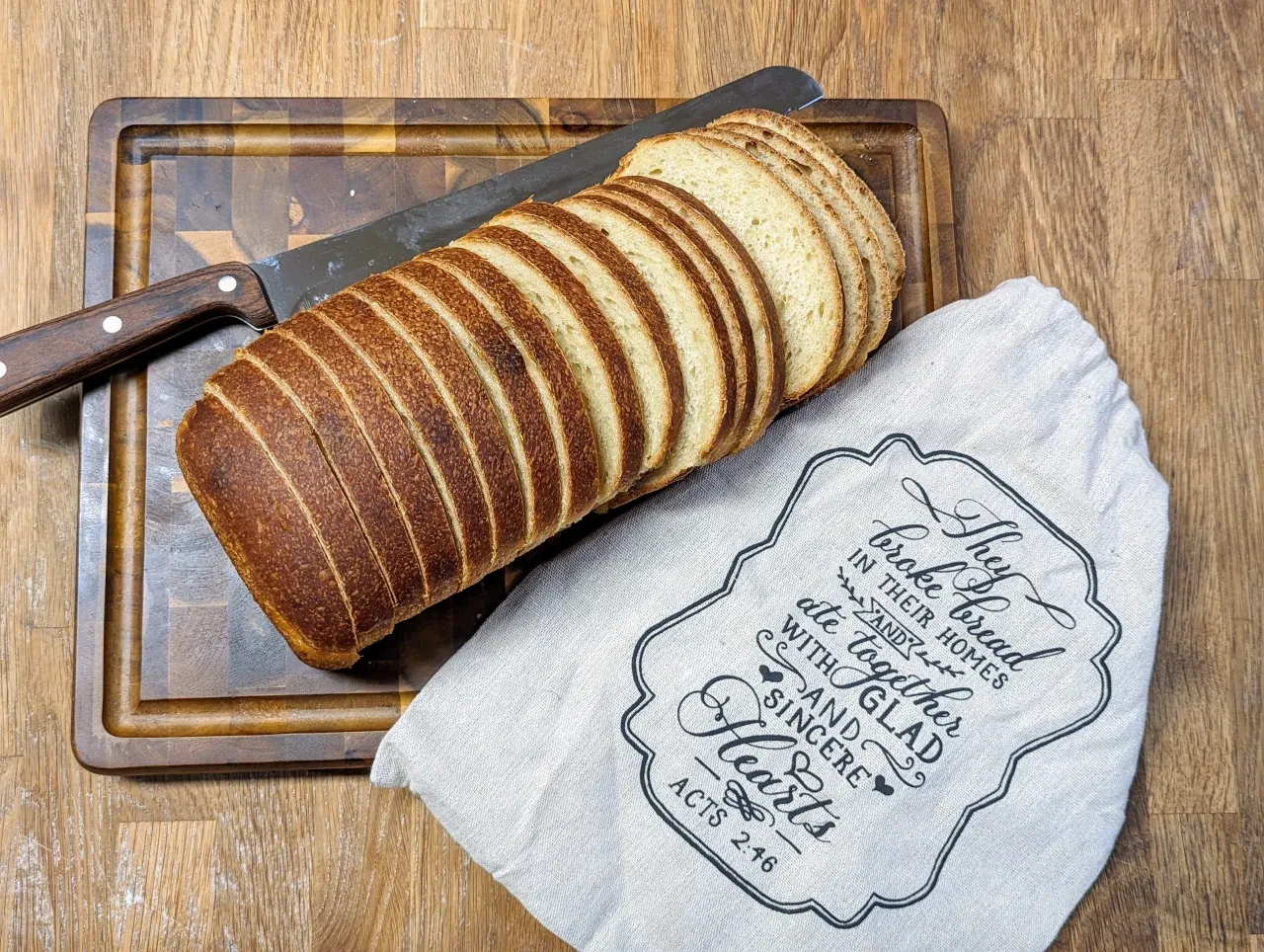 Sliced sourdough loaf on a cutting board with a branded cloth napkin