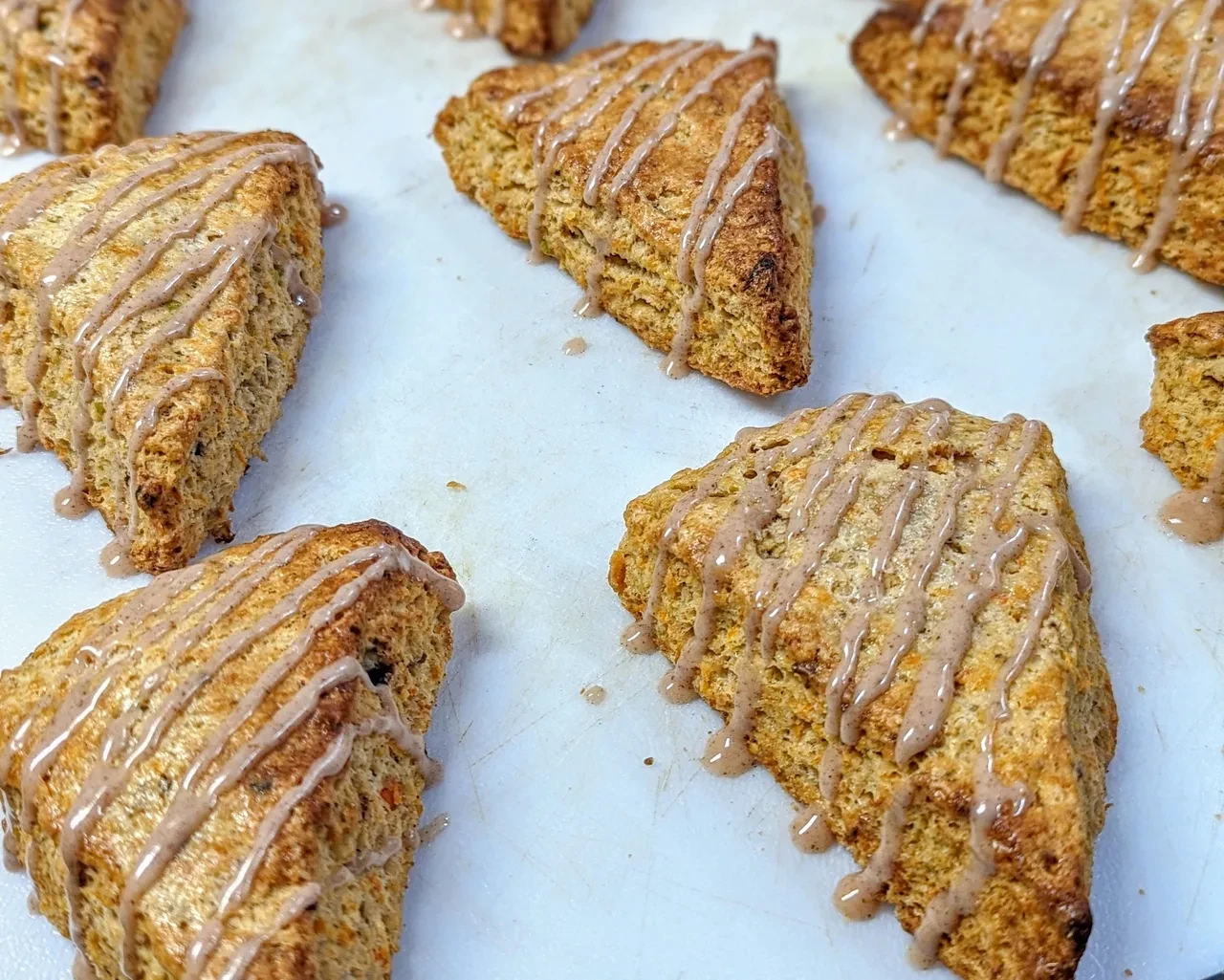 Glazed scones with drizzle on a parchment-lined baking sheet