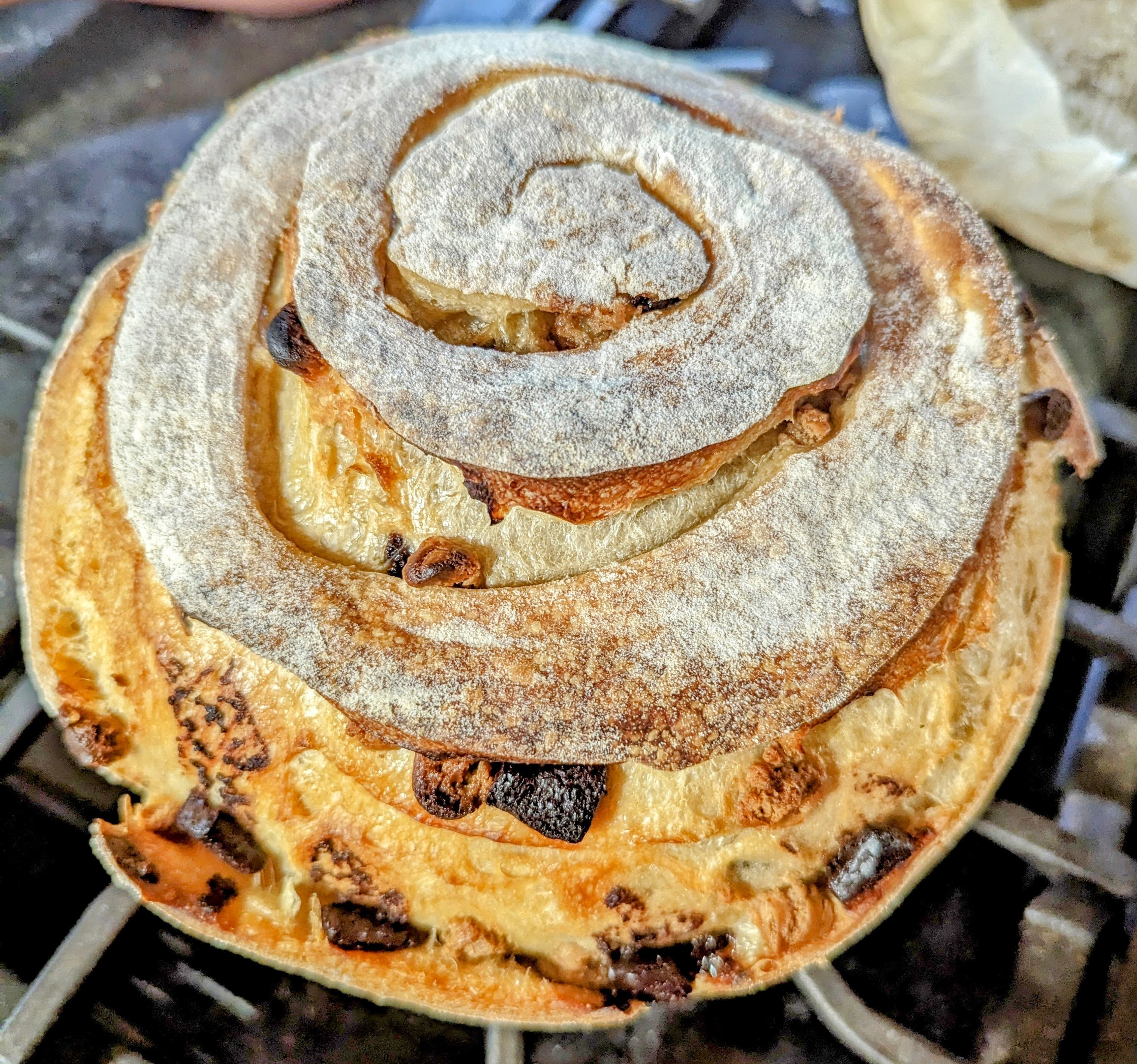 Freshly baked sourdough cinnamon roll with powdered sugar on a cooling rack