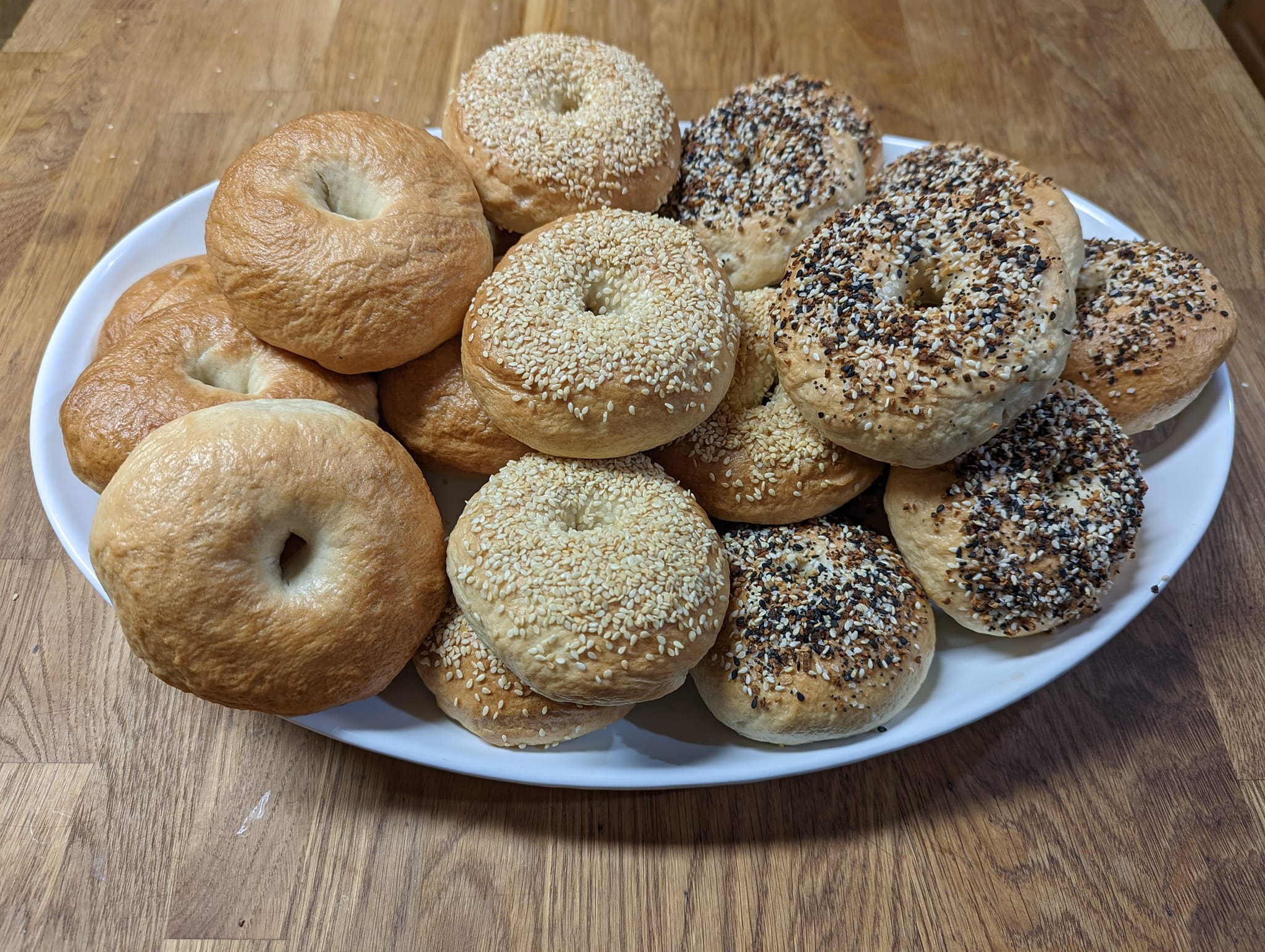 Assorted bagels — plain, sesame, and everything — on a white platter